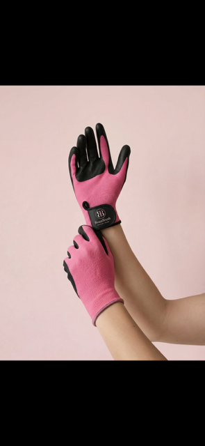 Two hands wearing pink Beaut Brush gloves with black textured palms, against a blush background.